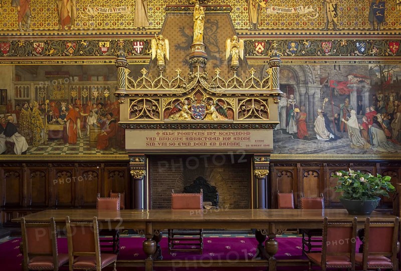 Interior of Bruges' city hall showing the Gothic hall with monumental mantelpiece and 19th century murals