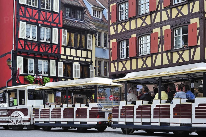 Colorful facades of timber framed houses and sightseeing train with tourists at Colmar