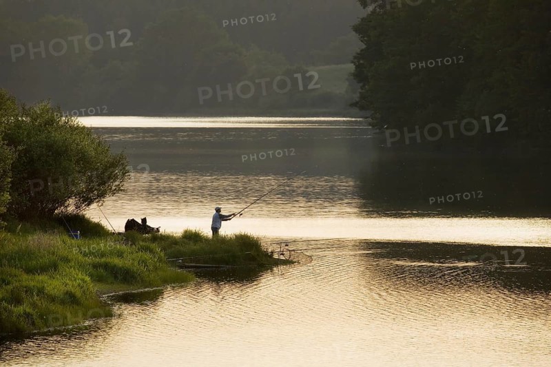Angler fishing at sunset at the Buetgenbach reservoir in the Hautes Fagnes