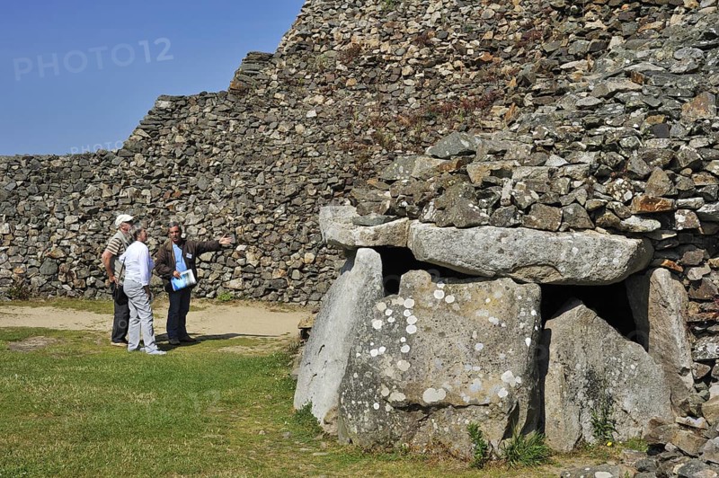Tourists with guide visiting entrance to one of the chambers of the Cairn of Barnenez