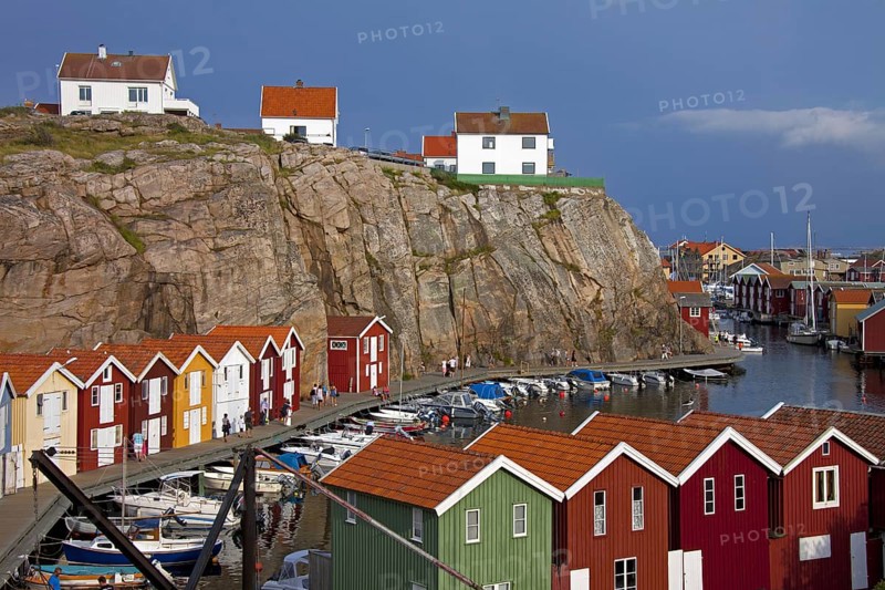 Colourful traditional fishing huts and boathouses along wooden pier at Smoegen