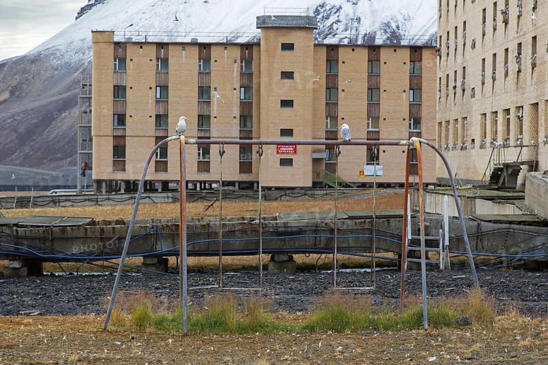 Hotel Tulpan and old swing on children's playground at Pyramiden