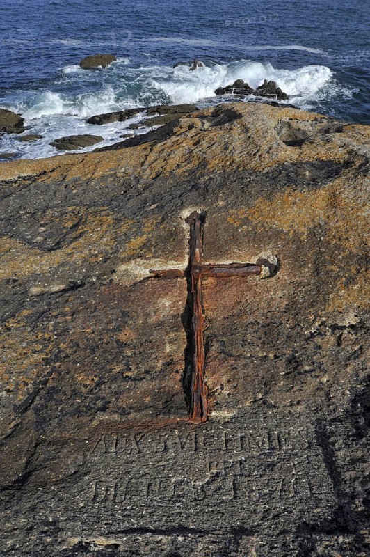 Iron cross embedded in the rock Rocher du Prefet at the coast in Saint-Guenole