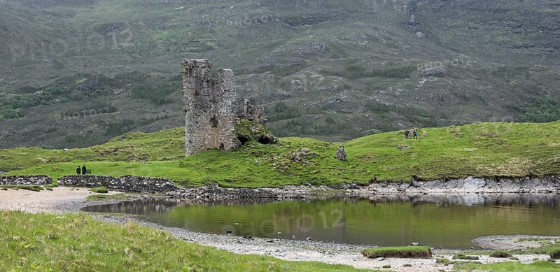 Tourists visiting 16th century Ardvreck Castle ruin at Loch Assynt in the Scottish Highlands