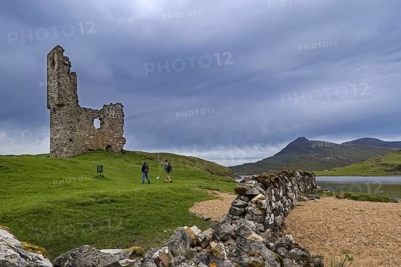 Tourists visiting 16th century Ardvreck Castle ruin at Loch Assynt in the Scottish Highlands
