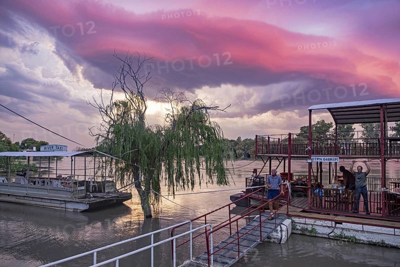 Western tourists and river taxis on the Orange river at sunset near Upington