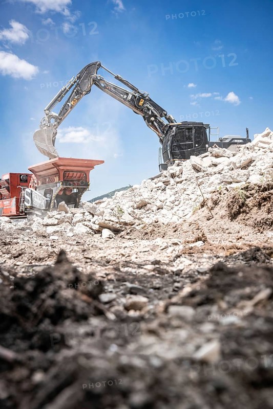 Black tracked excavator during demolition recycling on construction site