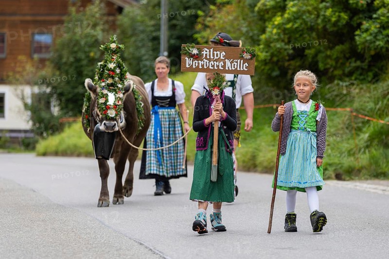 Girl in traditional traditional costume carrying alpine shield