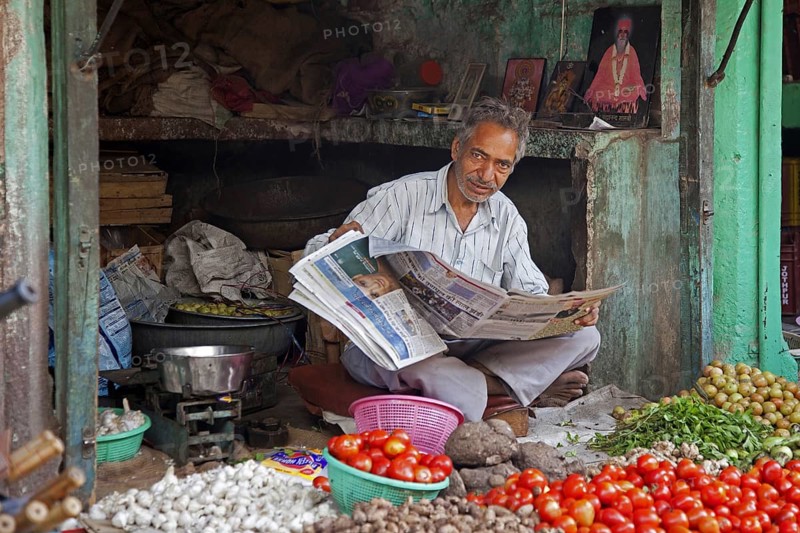 Shopkeeper reading newspaper in grocery shop at Jodhpur