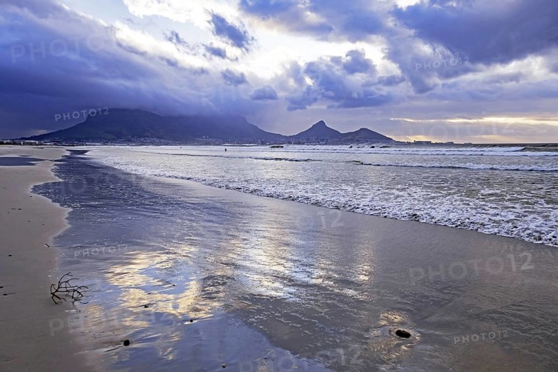 Rain clouds over the Table Mountain and sandy Sunset Beach on Woodbridge Island near Cape Town