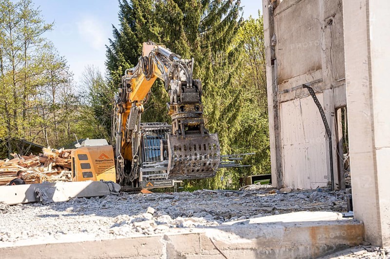 Yellow Liebherr crawler excavator with grapple recycling on demolition site