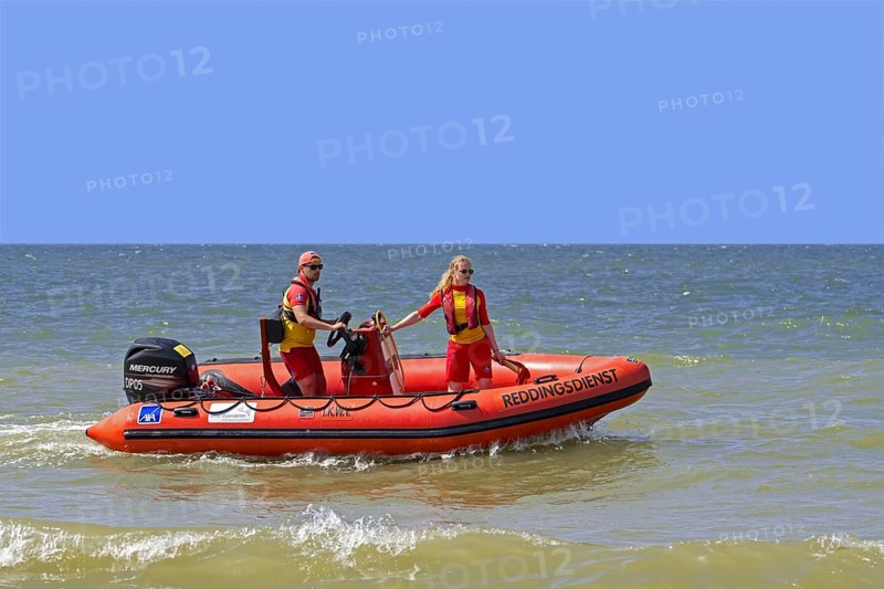 Young Belgian lifeguards in inflatable rescue boat patrolling along the North Sea coast in summer at Koksijde