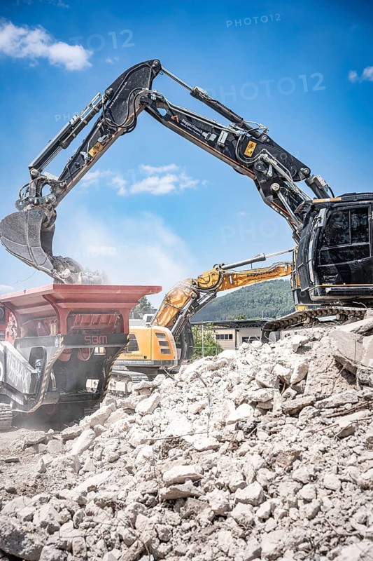 Black tracked excavator during demolition recycling on construction site
