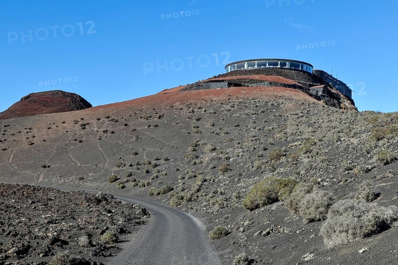 View of volcanic hilltop with tourist centre in Timanfaya National Park with panoramic restaurant El Diablo designed by Cesar Manrique