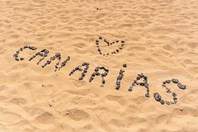 Canary name with black stones on the beach of the dunes of the Corralejo Natural Park