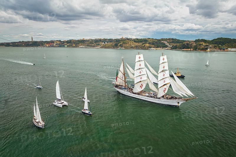 Aerial drone view of tall ships with sails sailing in Tagus river towards the Atlantic ocean in Lisbon