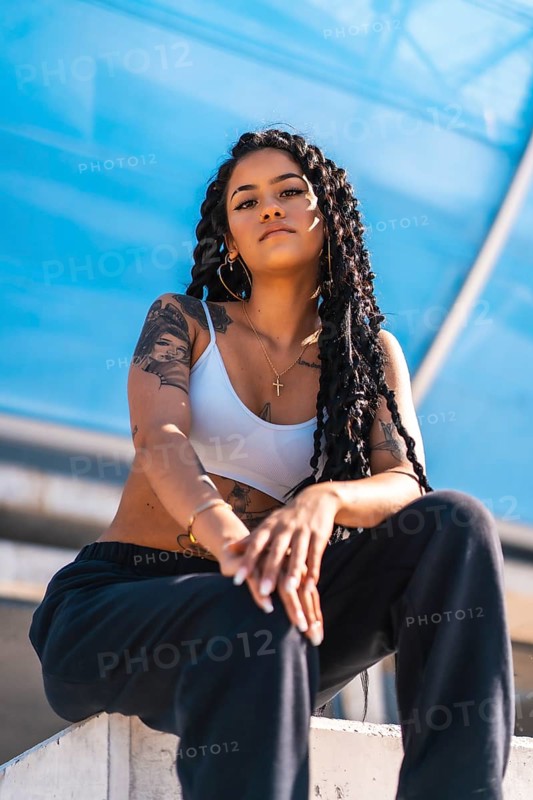 Young woman of black ethnicity with long braids and with tattoos