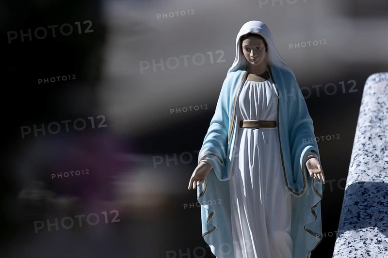 Kitschy figure of the Virgin Mary on a grave in a cemetery