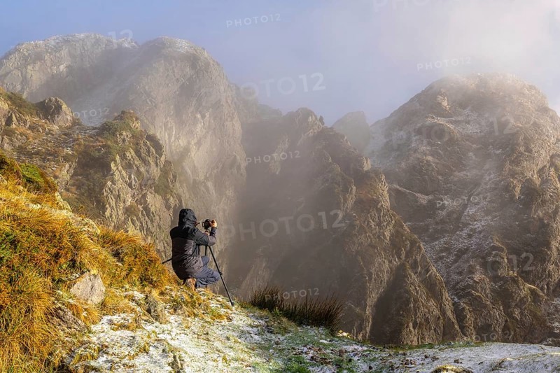 A photographer taking a photo with the tripod in the snowy winter sunset