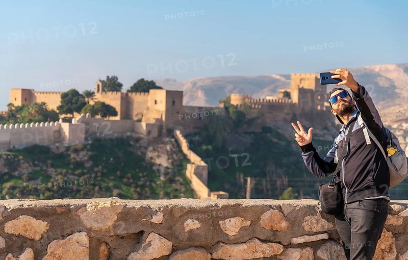 A young tourist taking a selfie at the viewpoint of Cerro San Cristobal de la Muralla de Jairan and the Alcazaba in the town of Almeria