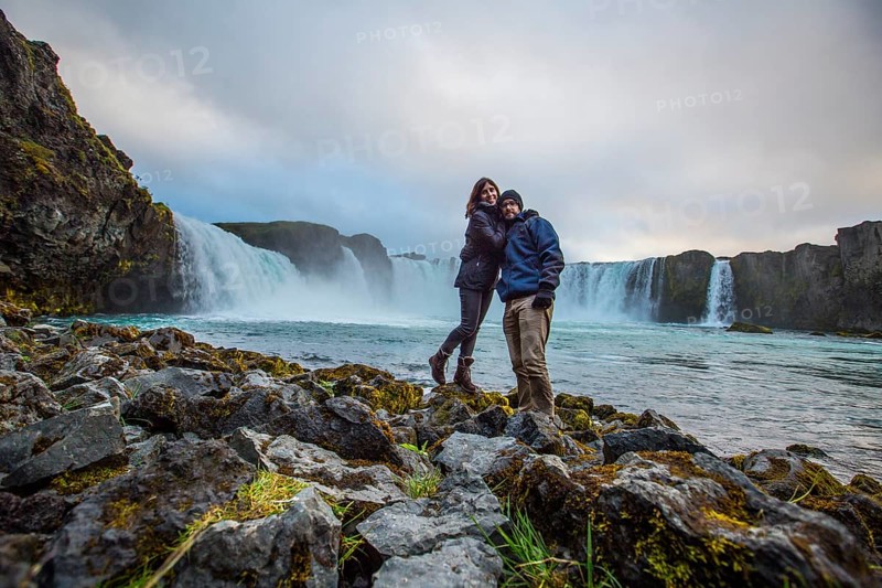 A young couple tourist looking at the Godafoss waterfall from above. Iceland
