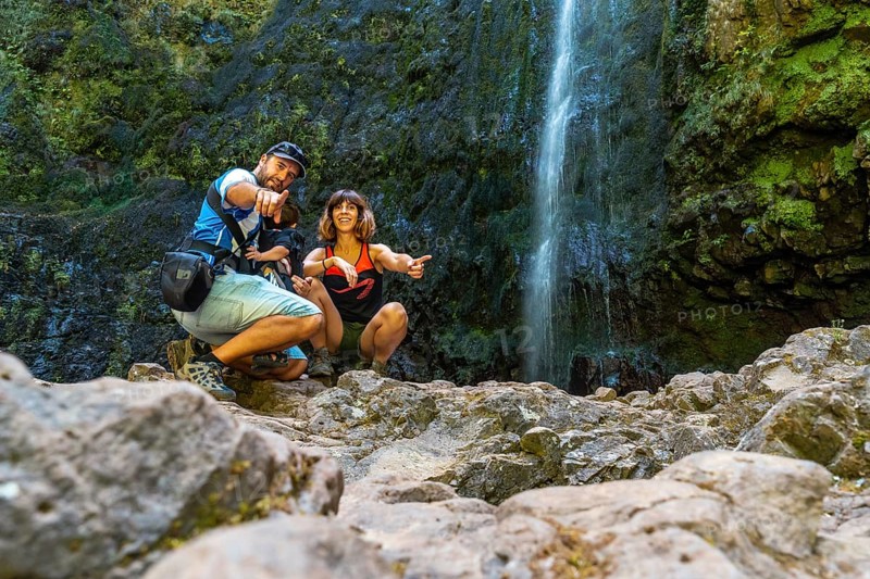 A family with their child in summer at the waterfall at Levada do Caldeirao Verde