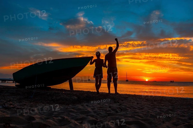 A couple watching the Roatan Sunset from West End. Honduras