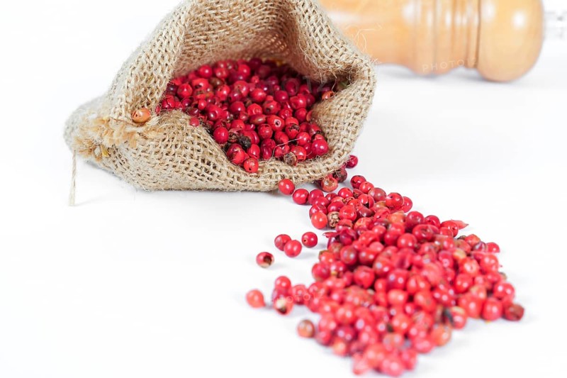 Pink peppercorns in a burlap bag isolated on white background and copy space