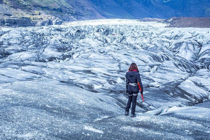 A young woman on her back with booties and hammer on the trekking of the Svinafellsjokull glacier. Iceland