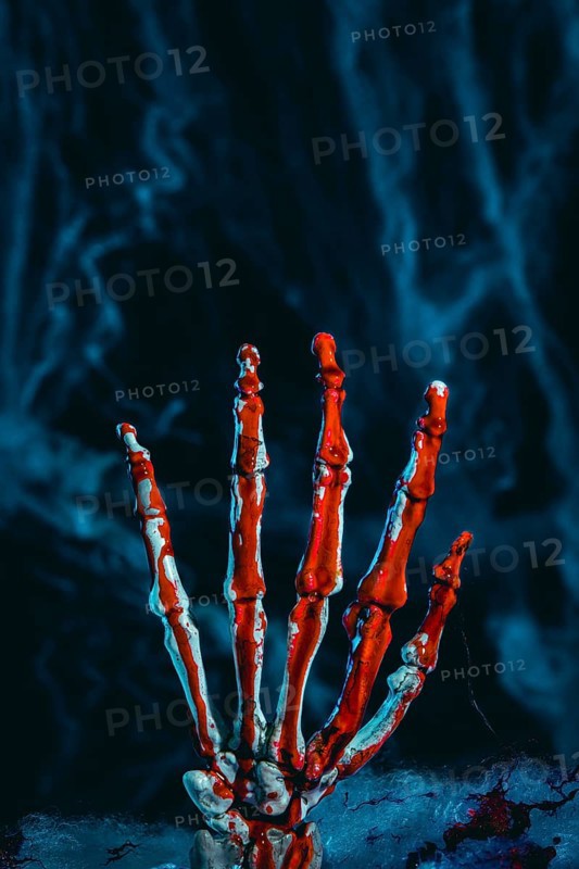 Bloodied skeleton hand in front of artificial cobwebs