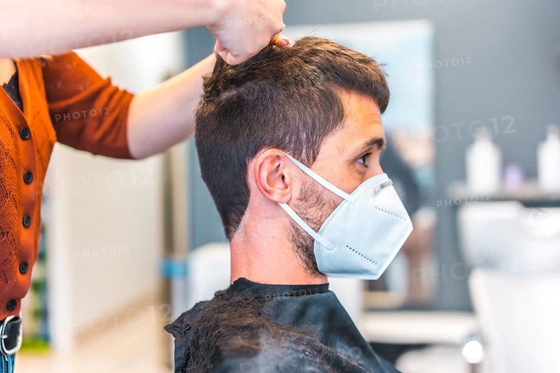 Hairdressers after the Coronavirus pandemic. Hairdresser with face mask and protective screen