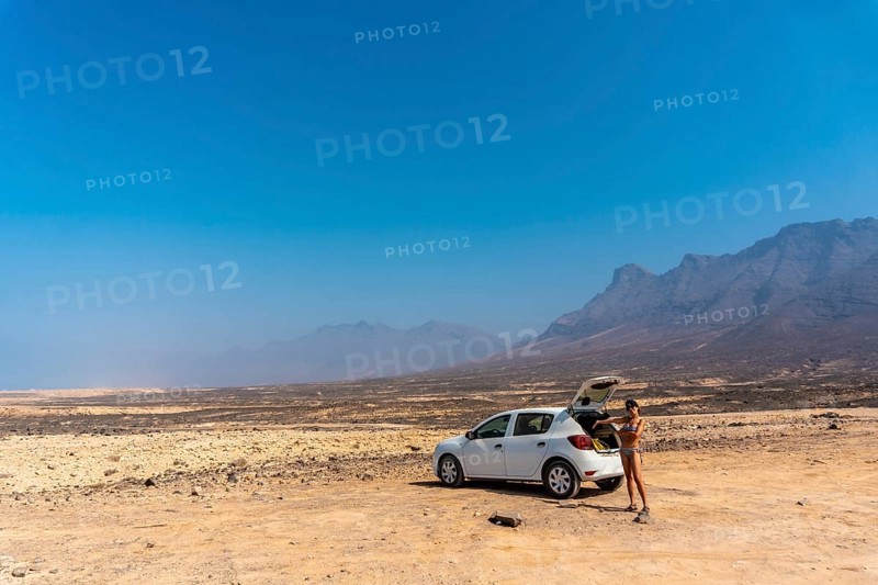 A young girl with the rental car on the Cofete beach of the Jandia natural park