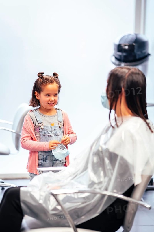 Client sitting waiting for the dye to dry and meanwhile talking to her daughter. Reopening with security measures for hairdressers in the Covid-19 pandemic