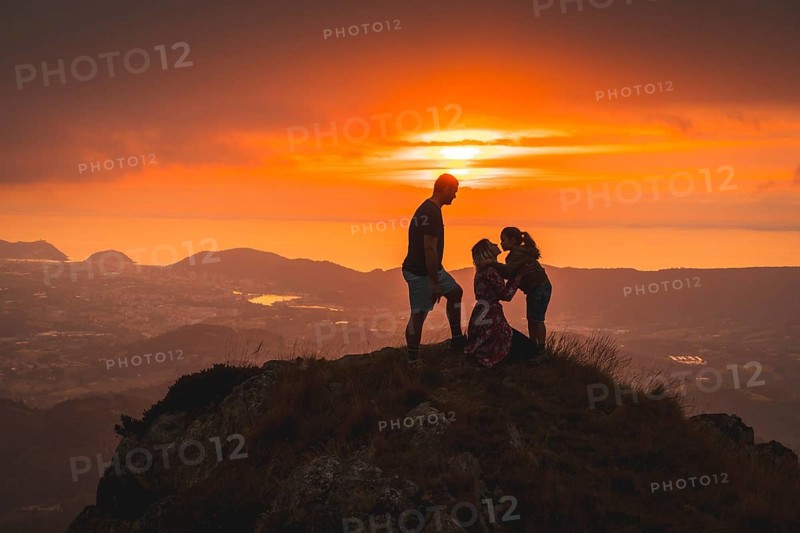 Parents with their son on top of a mountain at sunset