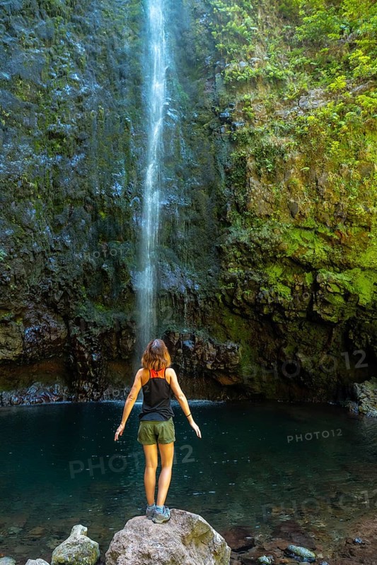 A young woman looking at the impressive waterfall at the Levada do Caldeirao Verde