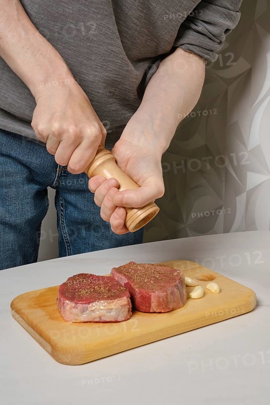 Sprinkling steak with salt from hand grinder