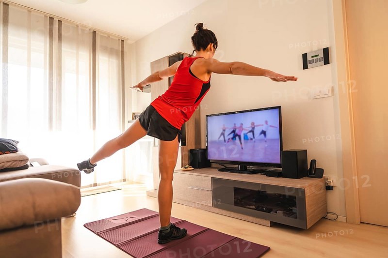 A young woman doing stretching in the room following the instructions of the online teacher. Sport in the covid19 quarantine at home