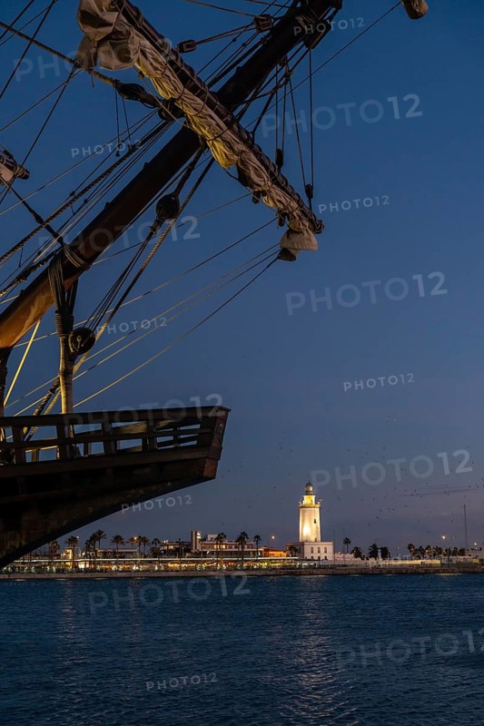 Old ship on the promenade of Muelle Uno in the Malagaport of the city of Malaga and in the background La Farola de Malaga