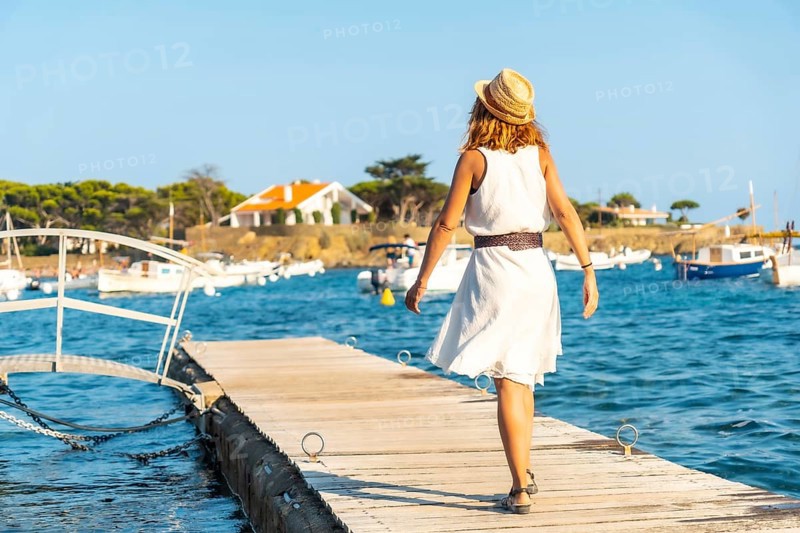 A young woman in a dress in Cadaques walking along the sea