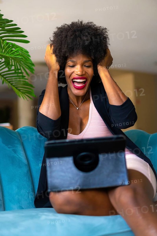 Young entrepreneur of black race and afro hair making a video call with great joy and amazement