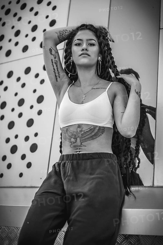 Young woman of black ethnicity with long braids and with tattoos