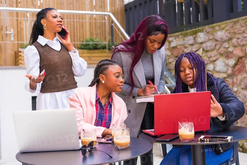 Young businesswomen of black ethnicity. At a business meeting in a cafeteria with computers and coffee on the table. Teamwork