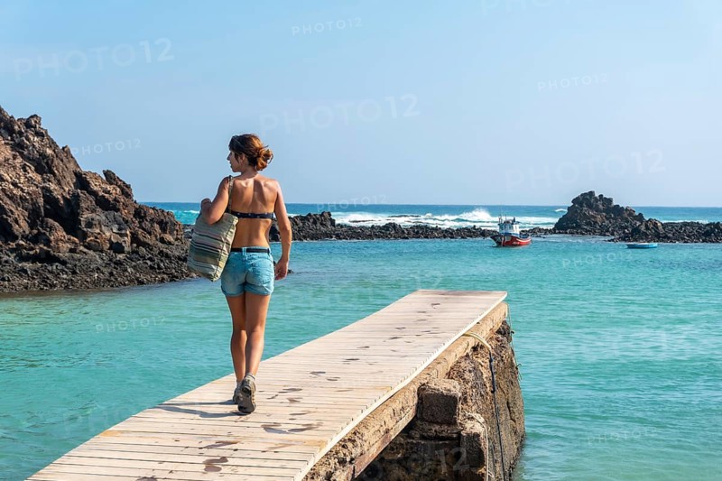A young woman walking along the wooden walkway on the Isla de Lobos