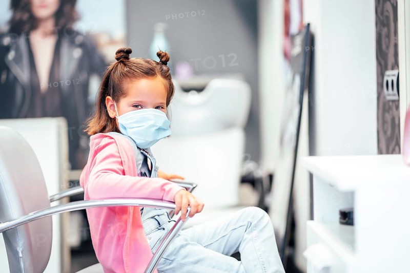 Girl sitting on the chair with pigtails finished. Reopening with security measures for hairdressers in the Covid-19 pandemic
