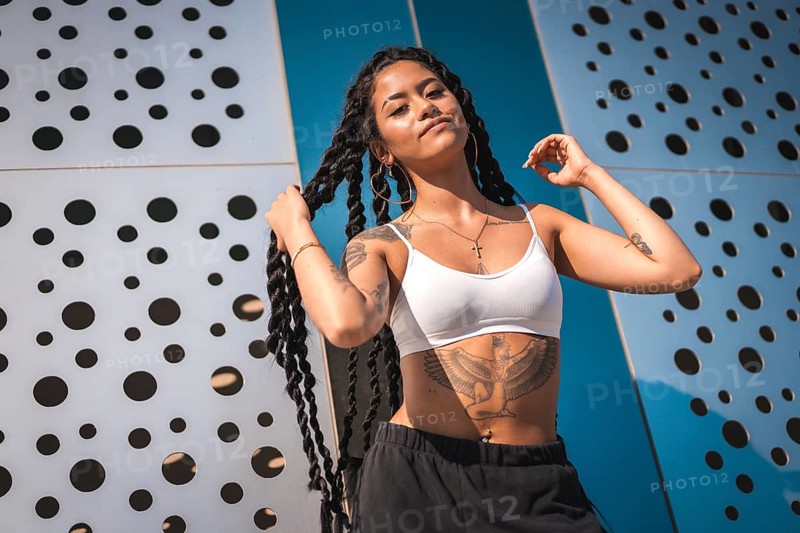 Young woman of black ethnicity with long braids and tattoos