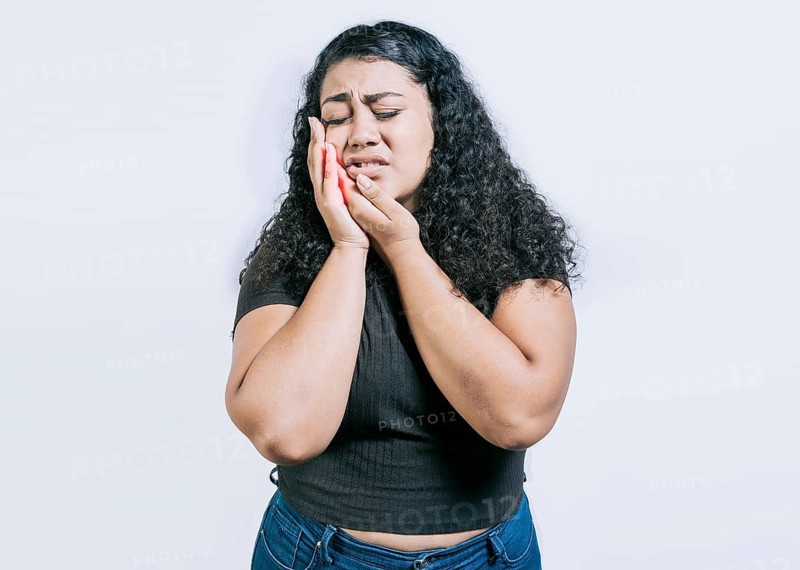 Young woman suffering with toothache isolated. Girl rubbing cheek with toothache on white background