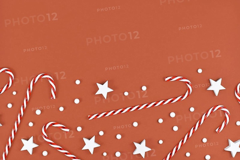 Christmas flat lay with candy canes and star and snow ornaments on brown background with empty copy space