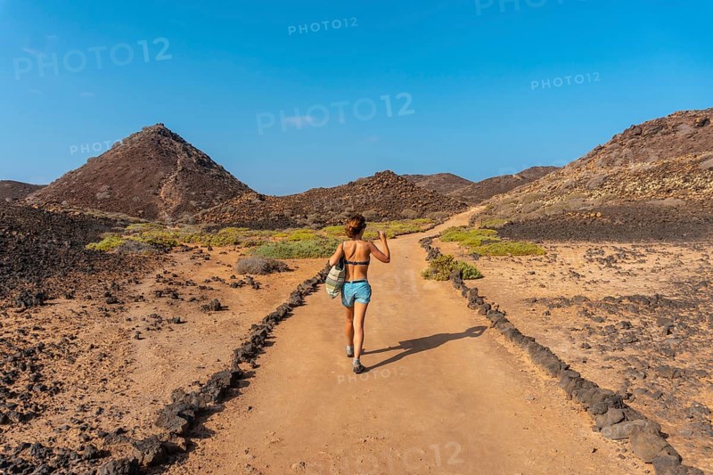 A young woman with a blue bikini on the trail to the north of the Isla de Lobos