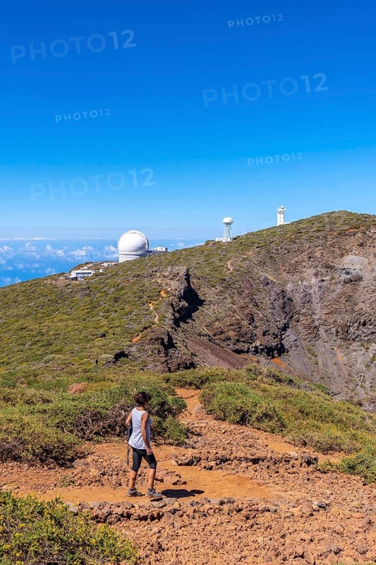 A young woman walking next to the telescopes of the Roque de los Muchachos National Park on top of the Caldera de Taburiente