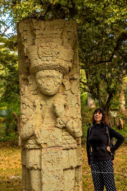 A woman in to detail of a figure in The temples of Copan Ruinas. Honduras